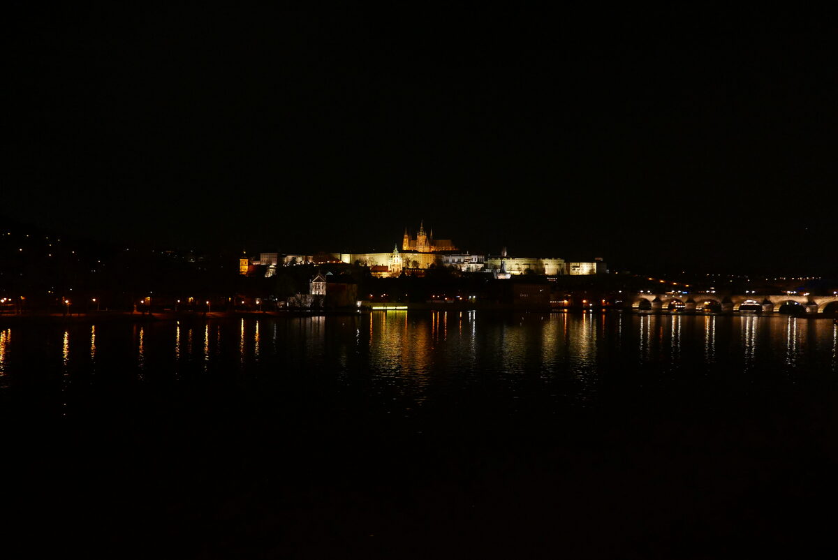 Prague Castle illuminated at night above the Vltava River